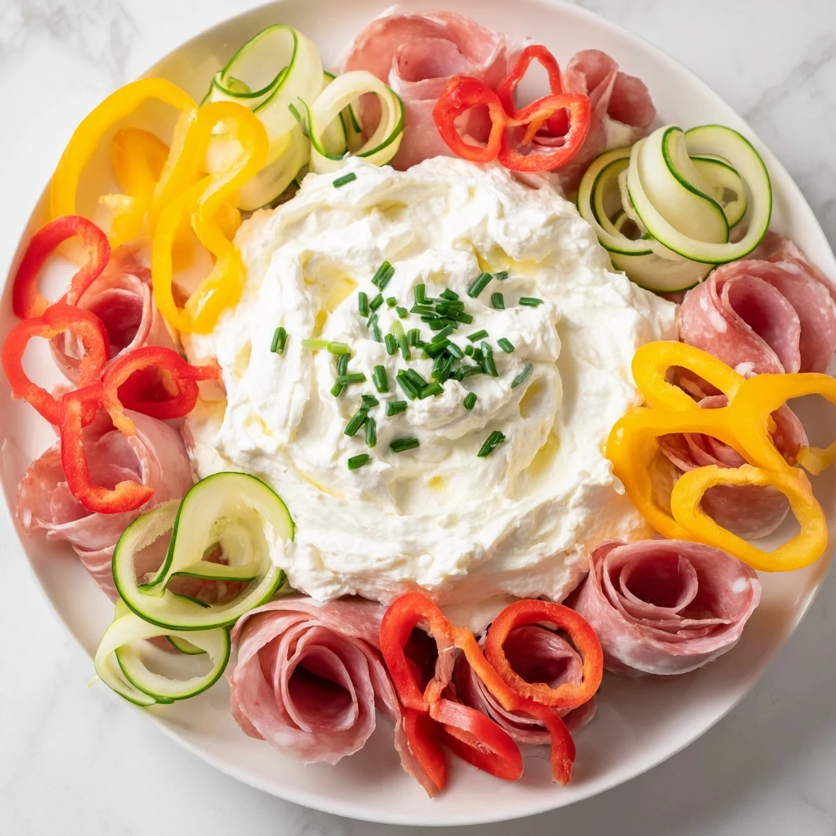 A colorful Medusa Curls party platter featuring radiating cured meats and pepper 'snakes'.
