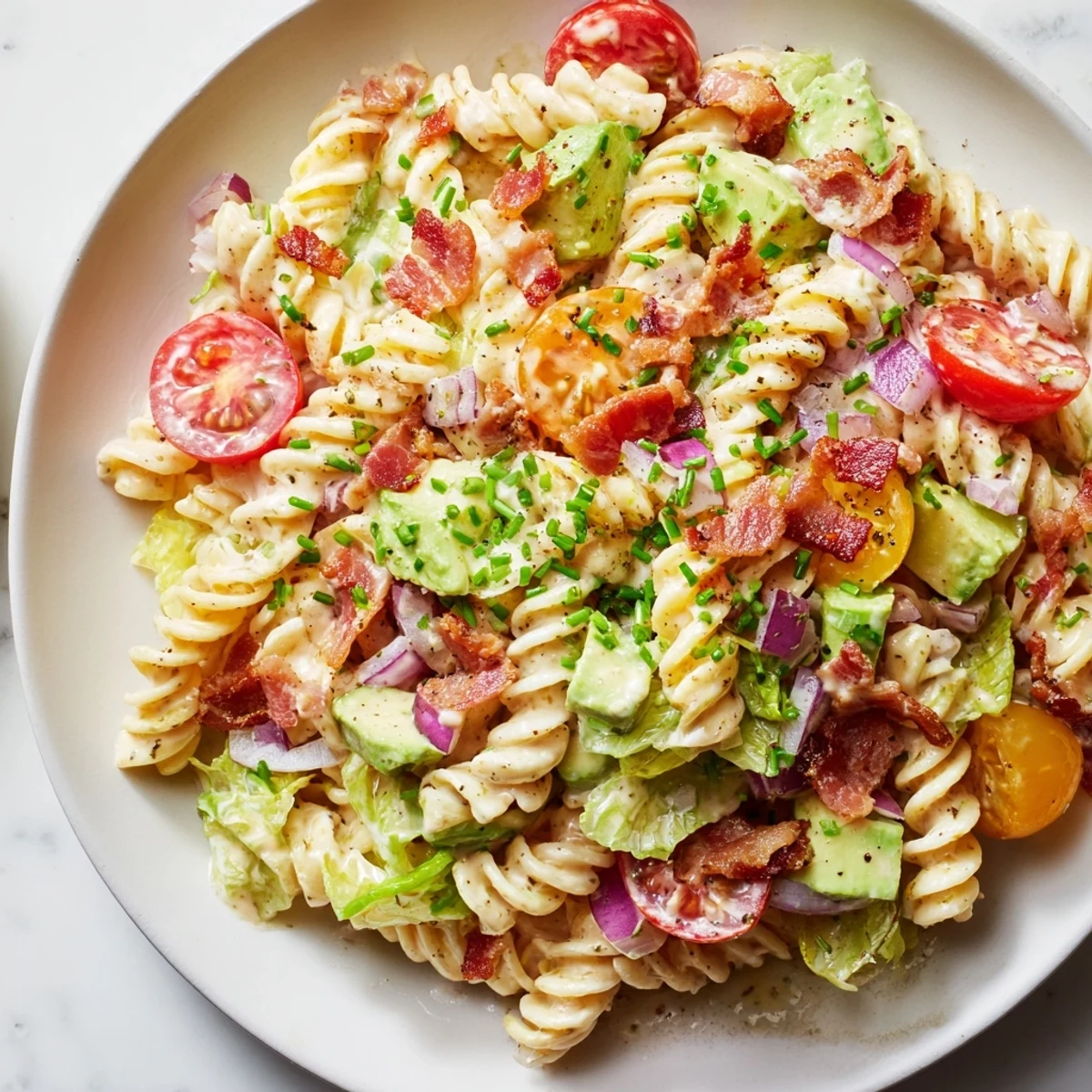 Close-up of a BLT Pasta Salad, showing fresh lettuce, pasta, and crispy bacon; a delicious lunch option.