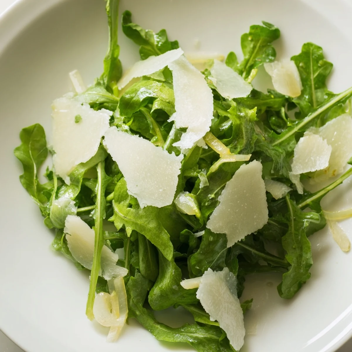 Crisp arugula salad with zesty lemon dressing, made with fresh ingredients and shaved Parmesan cheese.