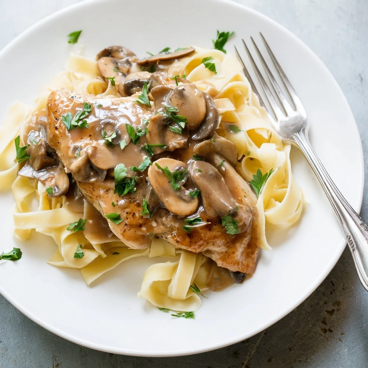 Goldbraun gebratene Hähnchenbrustfilets in einem cremigen Marsala-Wein-Sauce mit Pilzen auf einer Betten aus Al dente-Spaghetti.