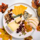 Vibrant Autumn Leaf Cheese Platter, showcasing colorful cheeses, crackers, and delicious, fresh fruit.