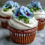 Zarte Vanille Cupcakes mit heller Buttercreme und bunten essbaren Frühlingsblüten, ein wunderschönes und köstliches Dessert für jeden Anlass.