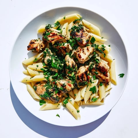 Chimichurri Chicken Pasta mit saftigem gegrilltem Hühnchen auf Al-dente-Penne in lebendiger, herber Kräutersauce serviert, frisch mit Zitronenscheiben garniert für südamerikanischen Fusion-Genuss.  