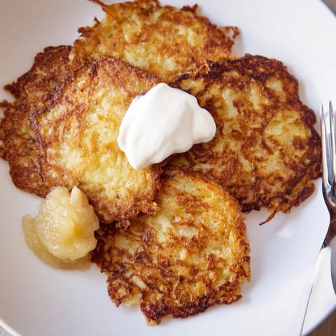 Hausgemachte deutsche Kartoffelpuffer, serviert mit einem Klecks Apfelmus, ein herzhaftes und süßes Vergnügen.