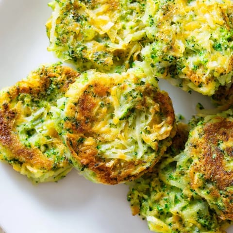 Golden-brown Cheesy Broccoli Patties: crispy veggie fritters speckled with herbs, ready to be enjoyed as a snack.