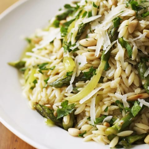 Asparagus Lemon Orzo Salad mit dünn gehobeltem Spargel und Parmesan in zitronigem Dressing auf breitem Teller.