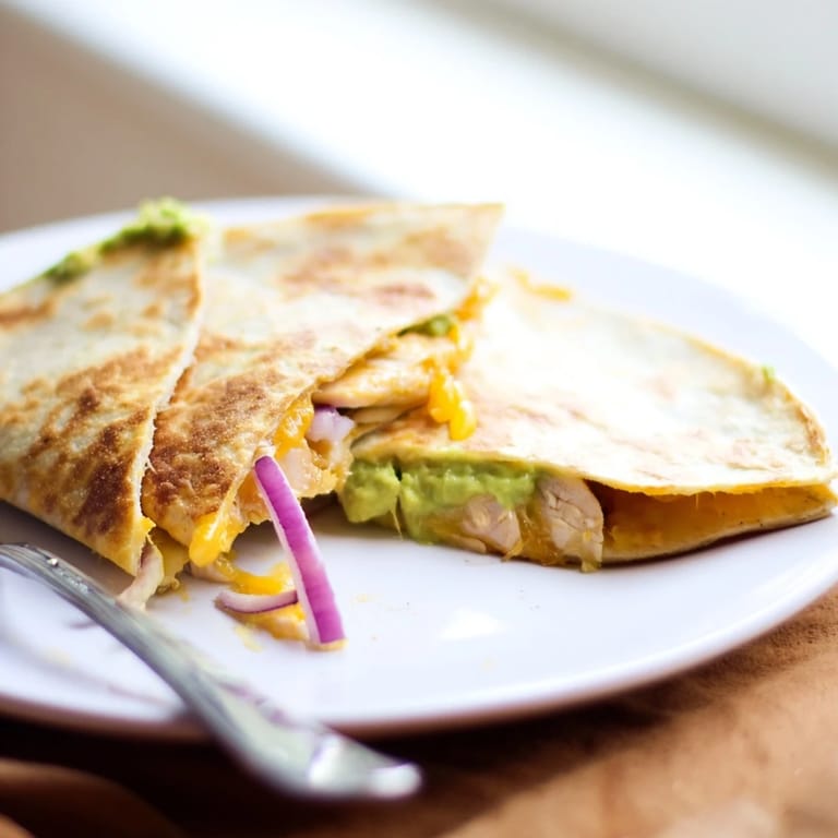 Perfectly grilled Chicken Avocado Quesadilla halves with golden tortilla edges, ready to dip into salsa or sour cream for a quick dinner.