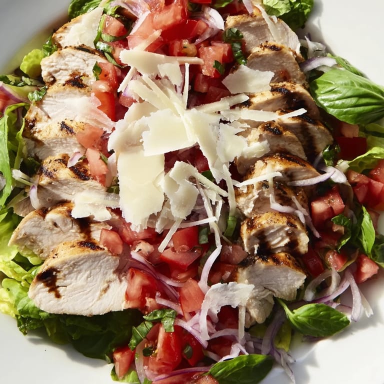 Bruschetta Chicken Salad served on a plate with shaved Parmesan and lemon wedges, perfect for a summery dinner.